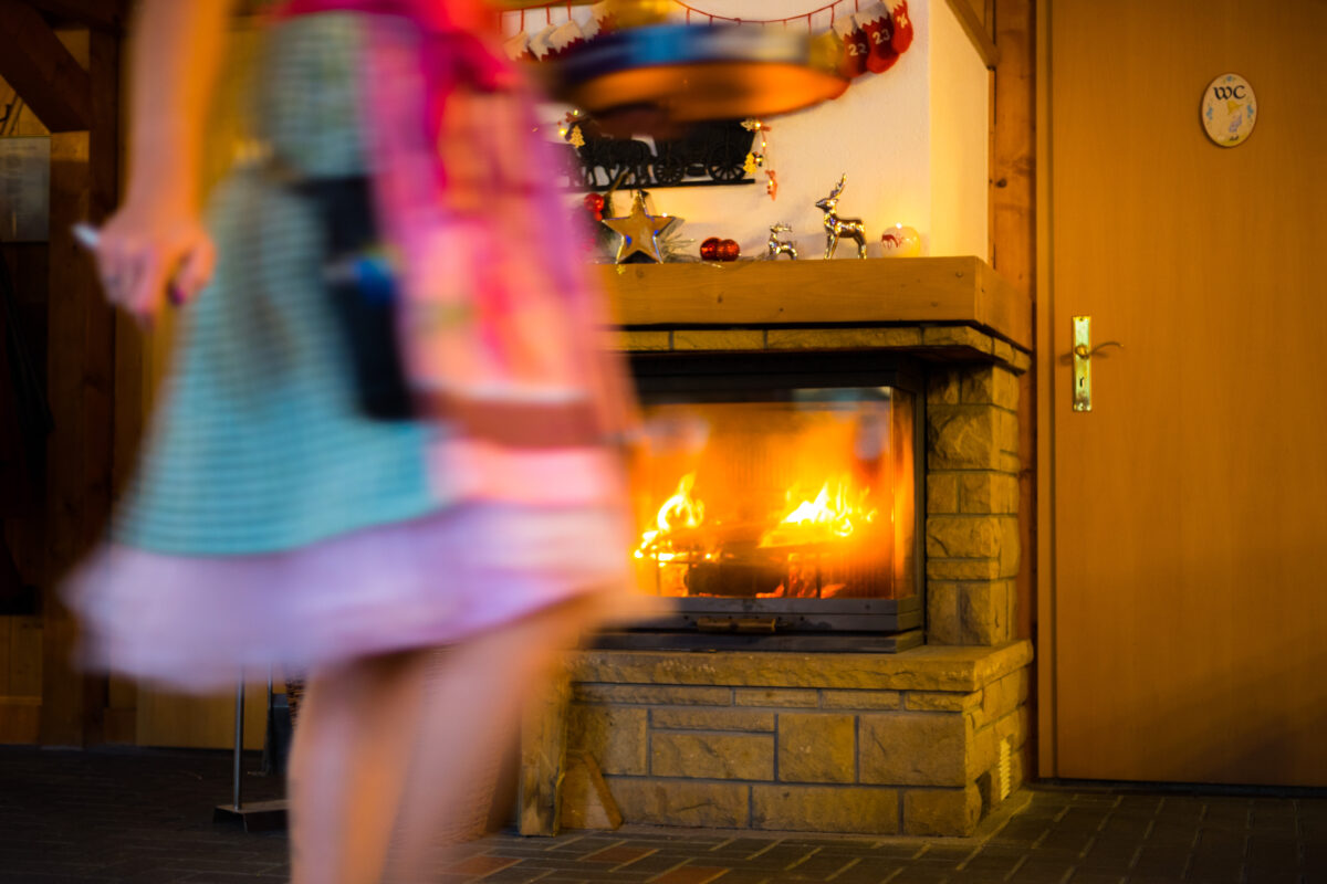 Bedienung im Dirndl läuft am Kamin in Weihnachtsstimmung vorbei.